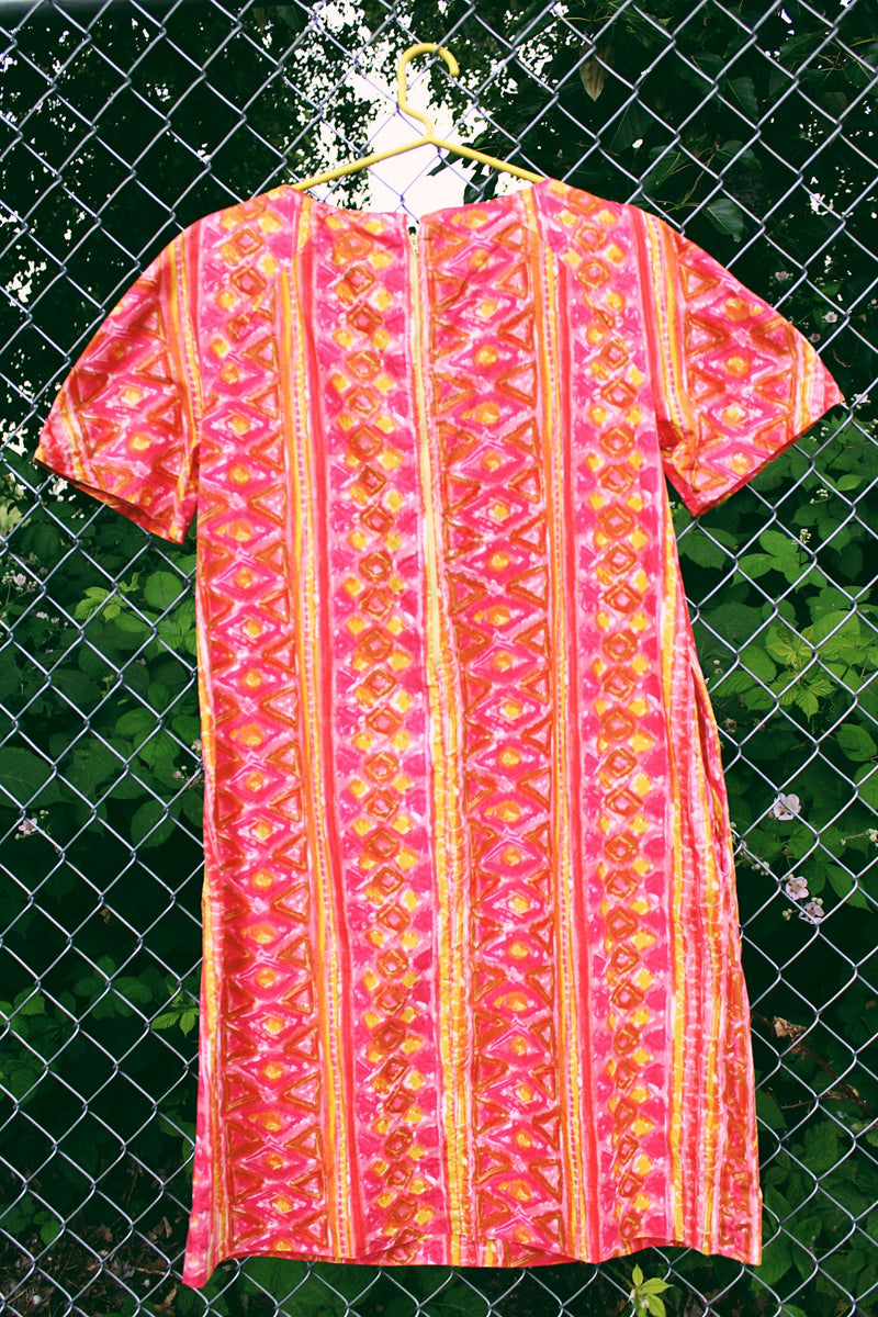 Women's vintage 1970's short sleeve midi length smock house dress in a pink, yellow, and light brown abstract print.