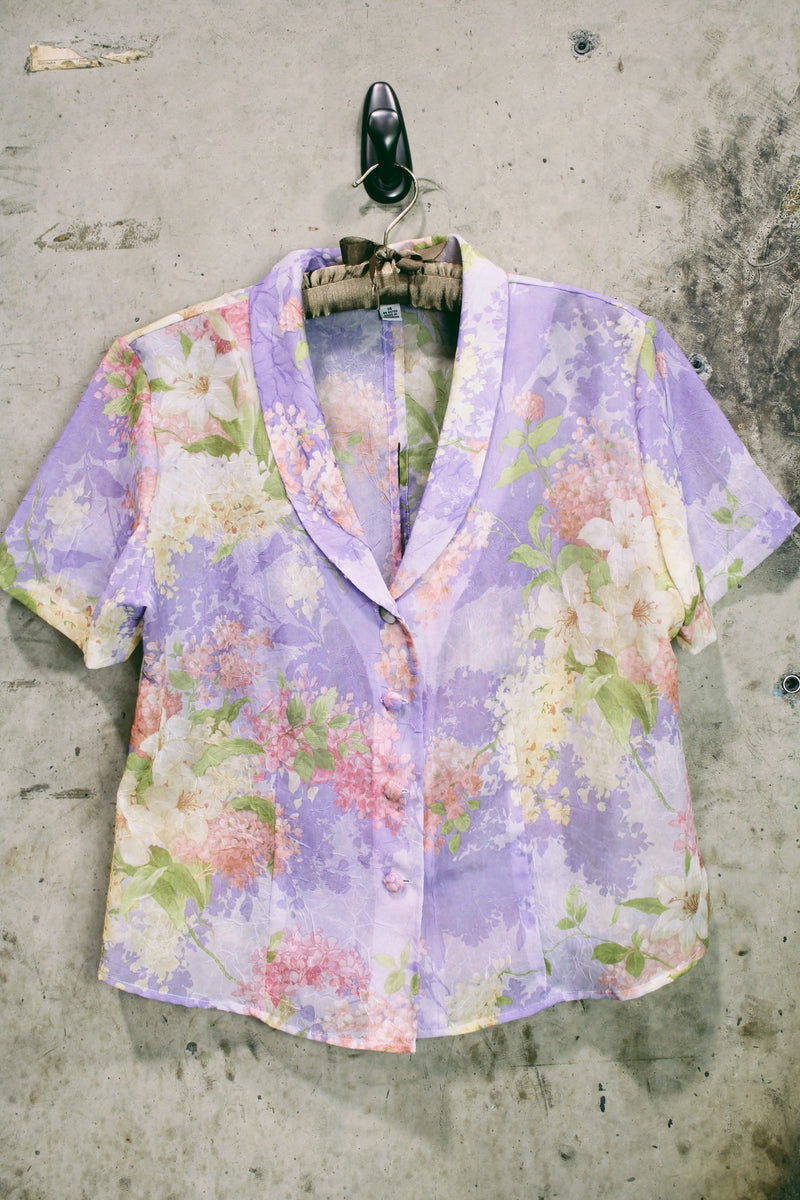 Women's vintage 1980's R&K Originals label short sleeve sheer button up blouse with all over purple and pink floral print with a slit in the back.