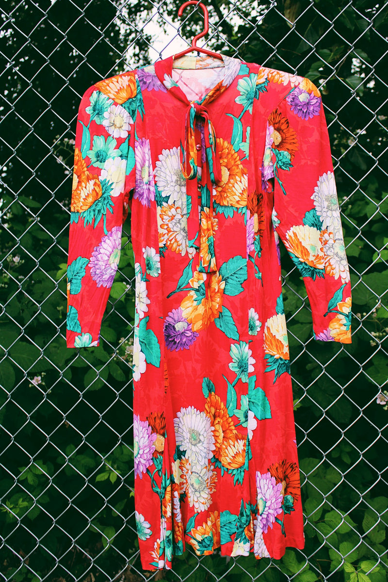 Women's vintage 1980's long sleeve mini dress with an attached tie neck. Red with all over floral print. Soft with shoulder pads.