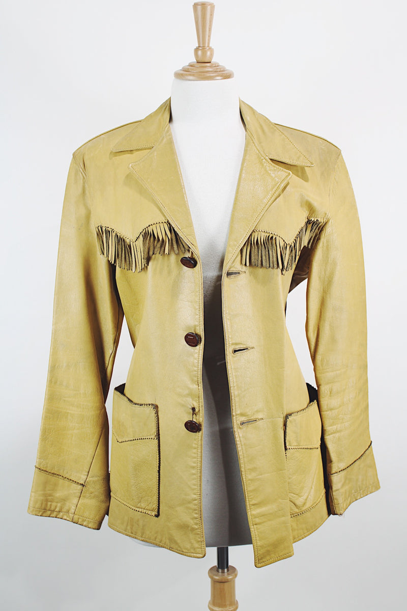 Men's or women's vintage 1950's long sleeve light tan colored genuine leather jacket with button front closure and fringe trim in front and back. 