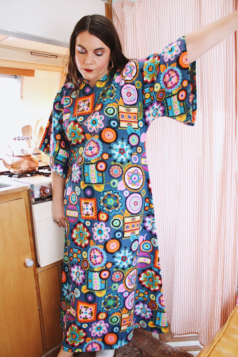 Women's vintage 1970's cotton material short sleeve maxi length dress with all over multicolored print. Has big flared sleeves and a V shaped neckline.