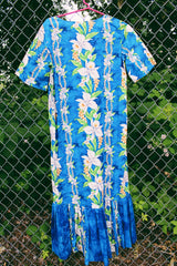 Women's vintage 1970's short sleeve Hawaiian print dress in blue with white flowers. Ruffle hem and maxi length.