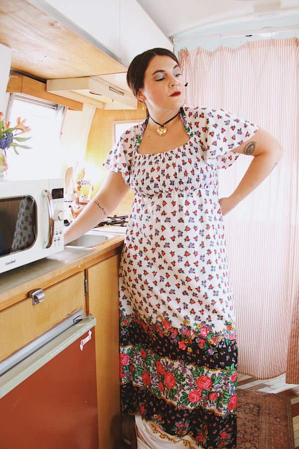 Women's vintage 1970's maxi length dress with flutter sleeves in white. Has an all over red and black ditsy floral print.