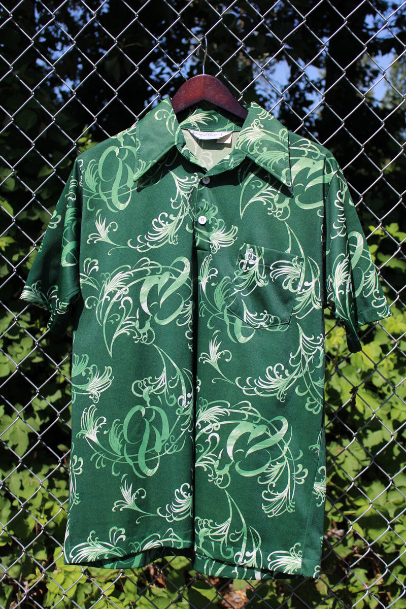 Men's vintage 1970's Grand Slam Munsignwear label short sleeve half button closure shirt with dagger collar in green with all over print. Polyester material.
