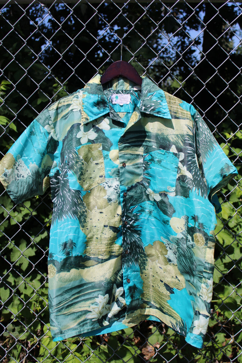 Men's vintage 1970's Waikiki Holiday label short sleeve button up Hawaiian print shirt with two chest pockets. Green and blue camera print in polyester material. 