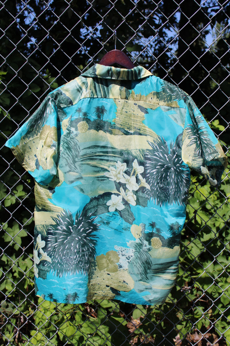 Men's vintage 1970's Waikiki Holiday label short sleeve button up Hawaiian print shirt with two chest pockets. Green and blue camera print in polyester material. 