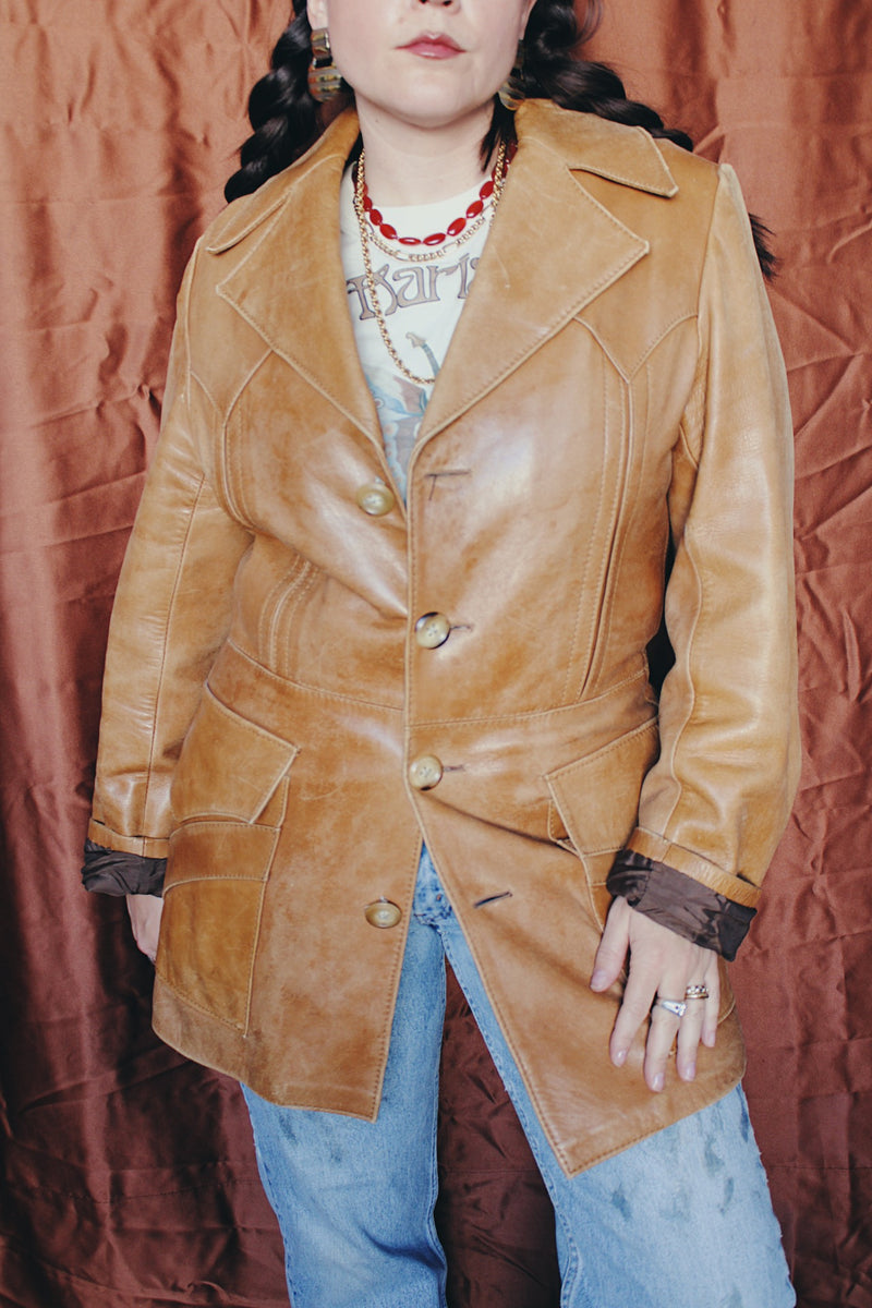 Women's or men's vintage 1970's Lou Pollack, Made in Spain label long sleeve long length tan camel brown colored leather blazer jacket with tortoise buttons up the front.