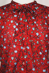 Women's vintage 1970's Donnkenny label long sleeve button up blouse with an attached tie neck. Red with all over blue ditsy floral print. 