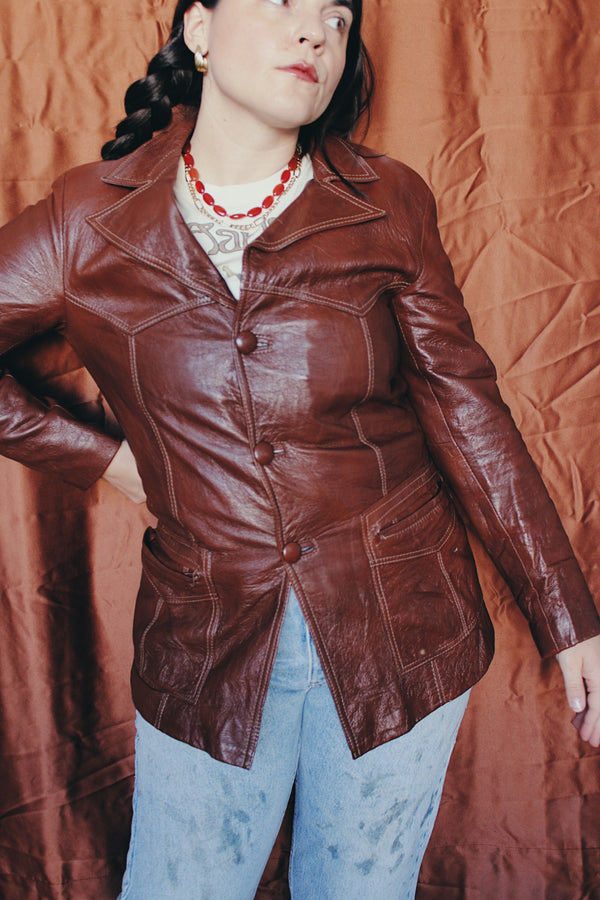 Women's or men's vintage 1970's chocolate brown colored leather jacket with leather buttons and double lapel. 