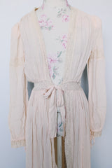 Women's vintage long sleeve long length pale pink sheer robe with an open tie front and lace trim. Has small shoulder pads and ties on cuffs.