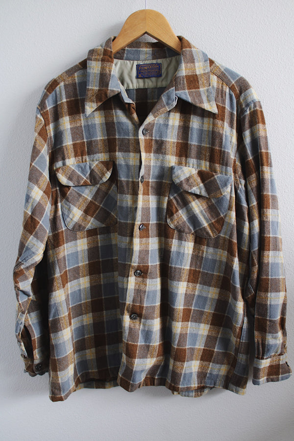Men's vintage 1960's Pendleton size XL long sleeve button up wool shirt in all over blue and brown plaid print. Two chest pockets.