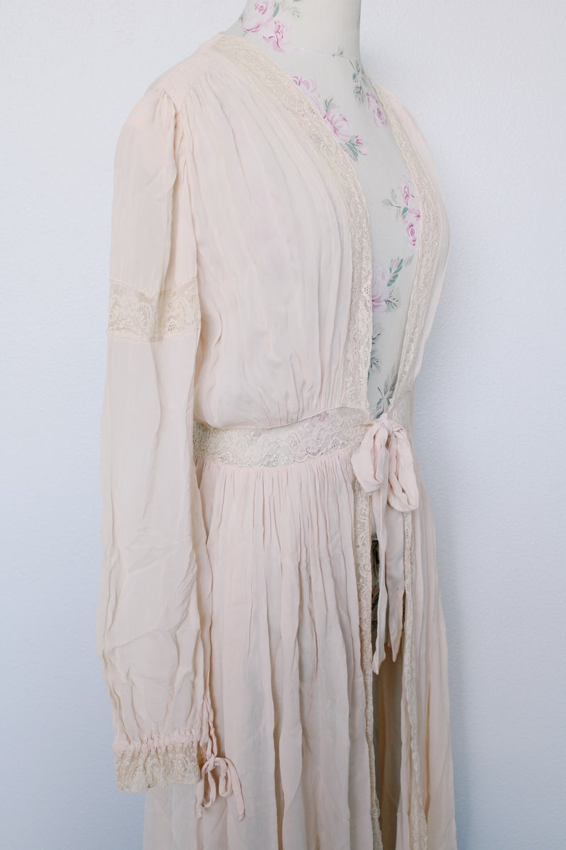 Women's vintage long sleeve long length pale pink sheer robe with an open tie front and lace trim. Has small shoulder pads and ties on cuffs.