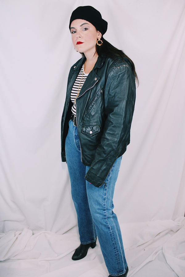 Men's or women's vintage 1980's long sleeve black leather moto jacket with all over silver hardware. Snap buttons, pockets with zippers, and zipper closure. 