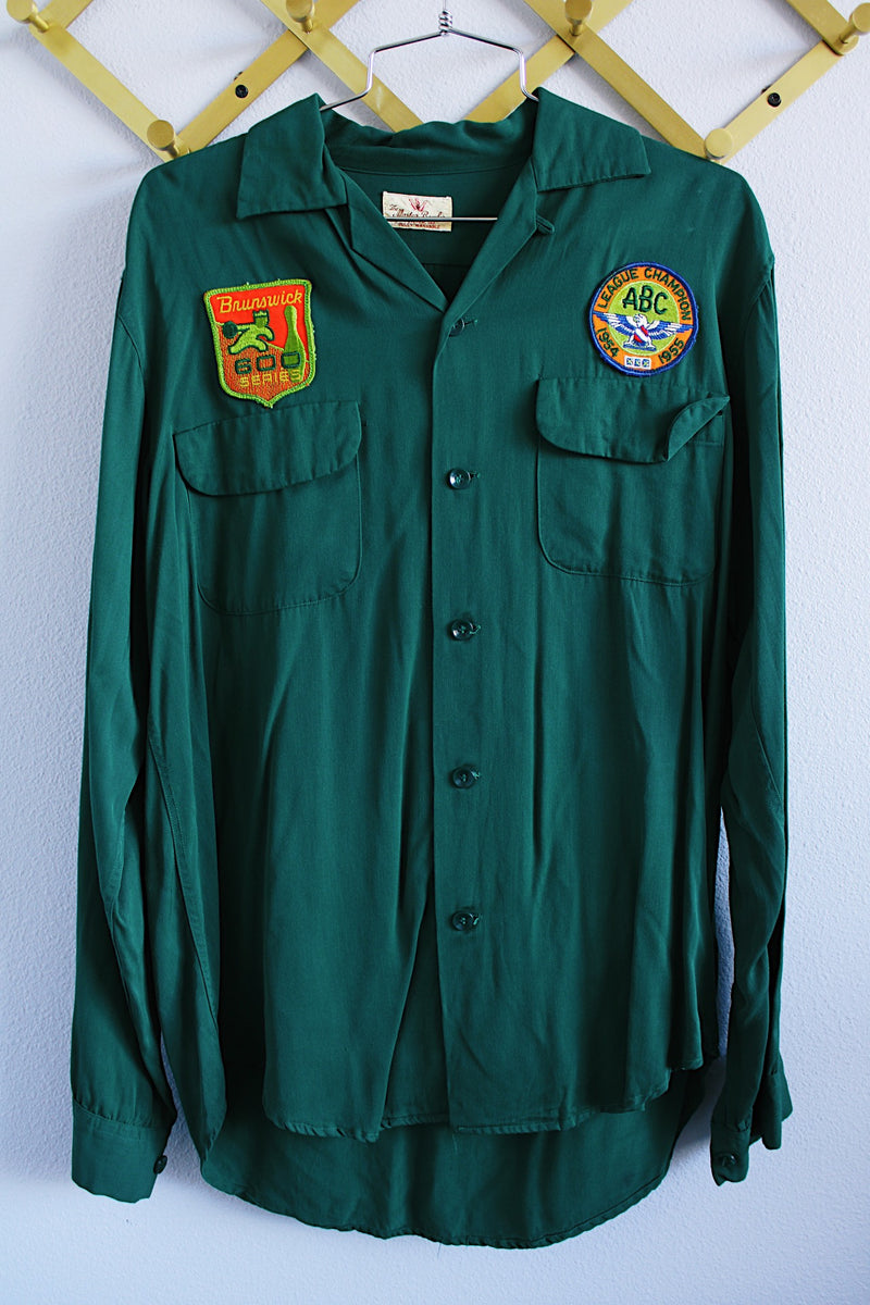 Men's vintage 1960's The Master Bowler label long sleeve forest green button up bowling shirt with collar, two chest pockets, and two bowling patches. 