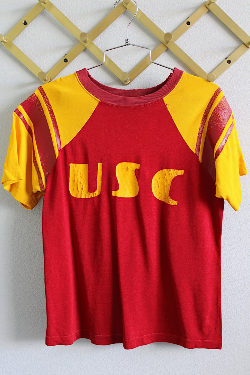 Women's or men's vintage 1970's Champion, Made in USA labels short sleeve sport jersey in maroon red and mustard yellow with USC graphic on the front and stripes on the sleeves.