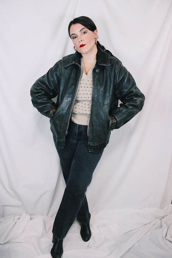 Men's vintage unknown, maybe around 40's-50's long sleeve black distressed leather  jacket with zipper front closure and buckles on cuffs.