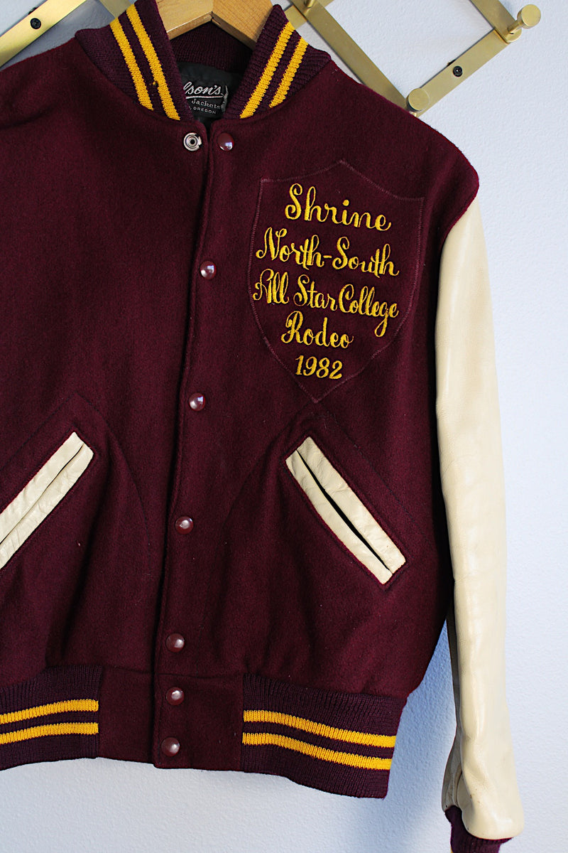 Women's or men's vintage 1982 Nelson's Jackets, Portland, Oregon label long sleeve letterman jacket with a maroon wool body and cream colored leather arms. Yellow stripped trim and popper buttons. Embroidery on chest.