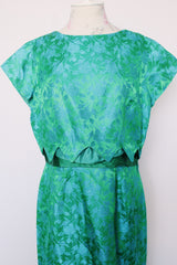Women's vintage 1960's short sleeve midi length green and blue stain dress. Subtle floral print and scalloped waist. Zipper in the back.