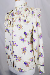 Women's vintage 1980's Val Lanne's label long sleeve button up blouse with ruffle details and pearl buttons. Cream color with all over purple floral print. 