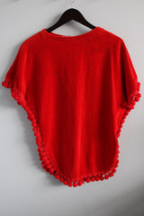 Women's vintage 1970's Aladdin label short sleeve red velour cape top with tasseled trim and holes for arms.