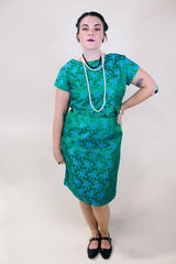 Women's vintage 1960's short sleeve midi length green and blue stain dress. Subtle floral print and scalloped waist. Zipper in the back.