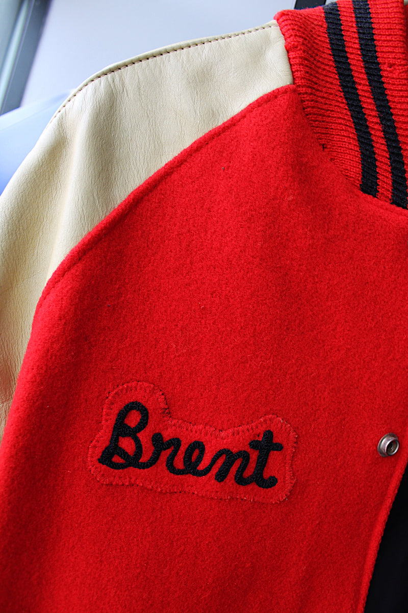 Men's vintage 1987 Nelson's Jackets, Portland, Oregon label long sleeve cream and red colored varsity letterman jacket in wool and nylon material. Has patches and pins.