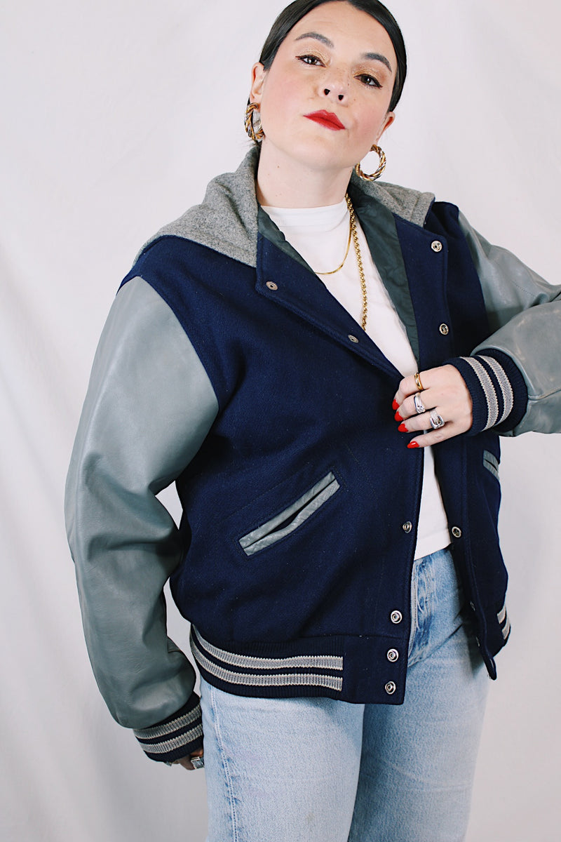 Men's or women's vintage 1980's Settlemein's, Portland, Oregon label long sleeve navy and grey varsity letterman jacket in wool, leather, and nylon. Snap buttons and hood.