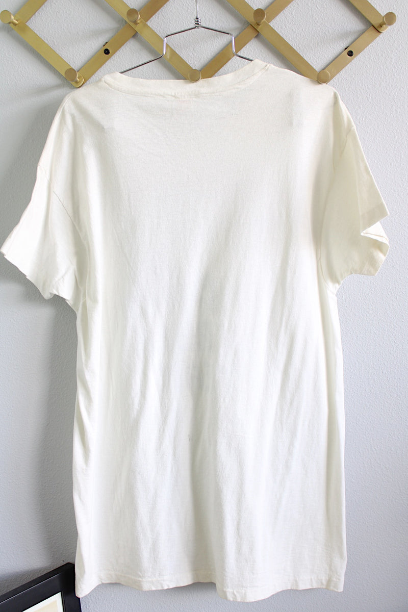 Women's or men's vintage 1970's Hanes short sleeve white t-shirt with blue lettering on the front. Ribbed neckline, long length, and 100% cotton material.