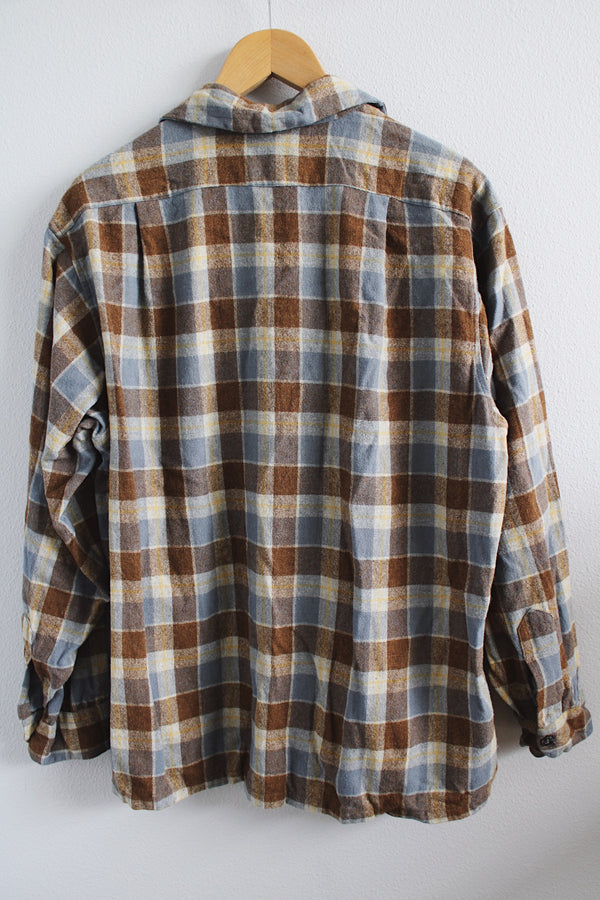 Men's vintage 1960's Pendleton size XL long sleeve button up wool shirt in all over blue and brown plaid print. Two chest pockets.
