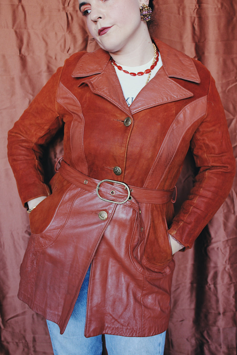 Women's vintage 1970's long sleeve button up burnt orange suede and leather jacket. Long length with matching belt.