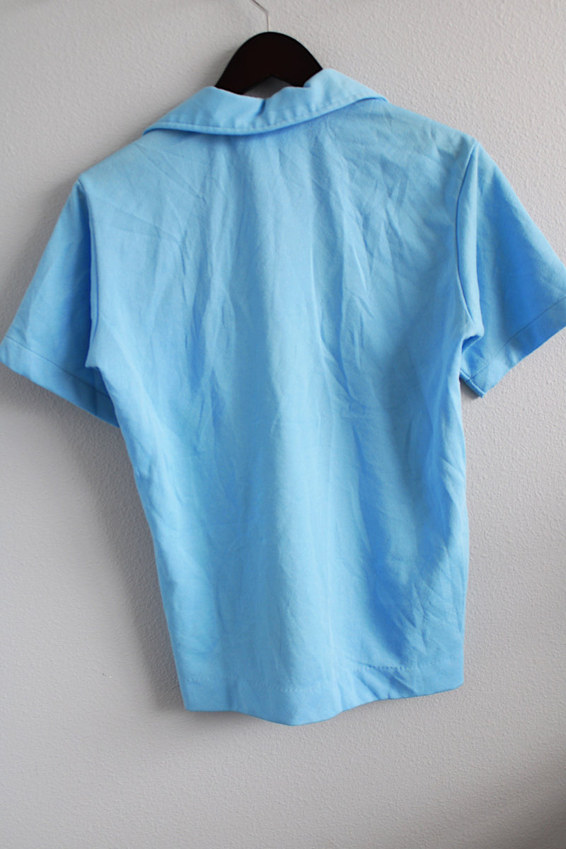 Men's or women's vintage 1970's Styled in California for JCPenney label short sleeve polo top in a light blue polyester material. Has a collar and half button closure.