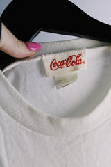 Women's or men's vintage 1986 Coca-Cola label short sleeve white tee with graphic on the front in a polyester and cotton material.