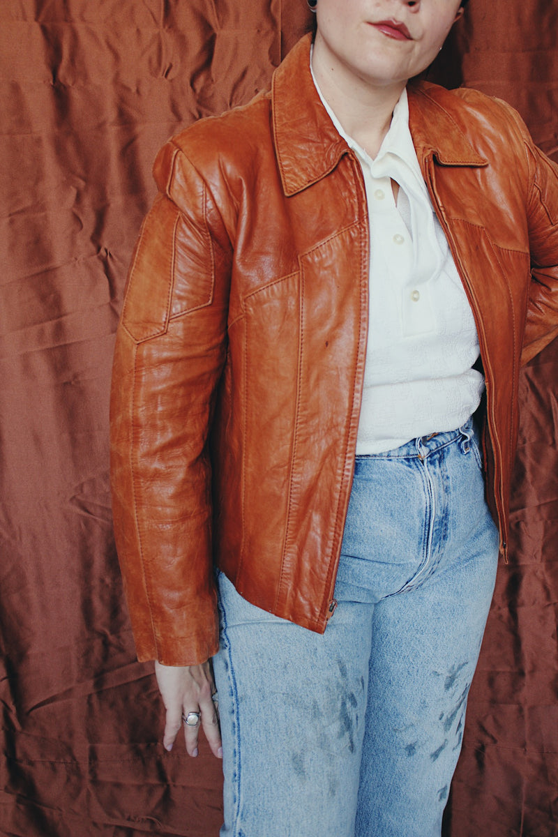 Women's or men's vintage 1970's Wilson label long sleeve burnt orange colored leather zip up jacket. Side pockets and dagger collar.