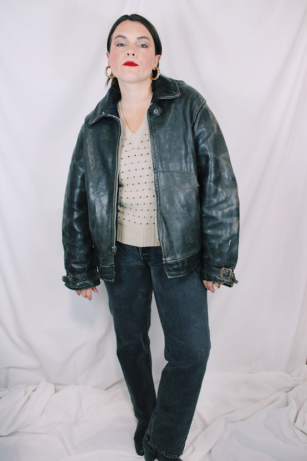 Men's vintage unknown, maybe around 40's-50's long sleeve black distressed leather  jacket with zipper front closure and buckles on cuffs.