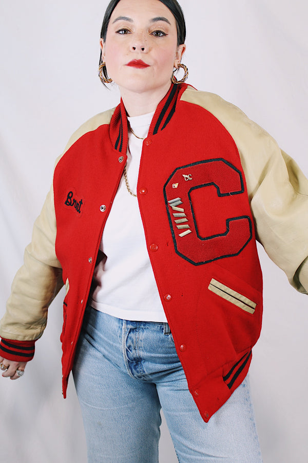 Men's vintage 1987 Nelson's Jackets, Portland, Oregon label long sleeve cream and red colored varsity letterman jacket in wool and nylon material. Has patches and pins.