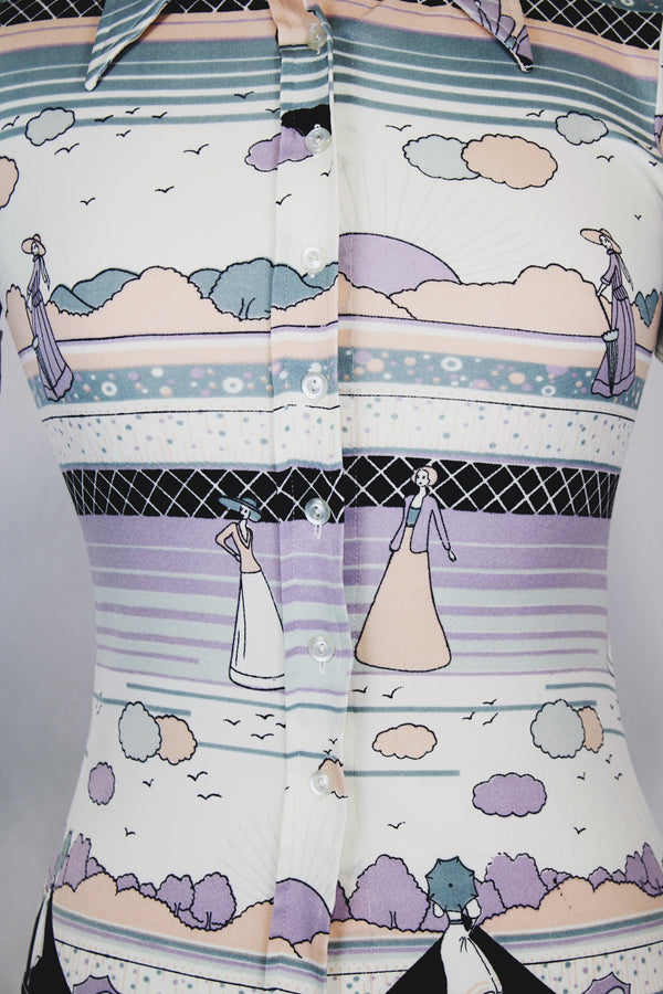 Women's vinttage 1970's Fritz label short sleeve button up blouse with dagger collar and all white, blue, and purple novelty print in a lightweight polyester material. 