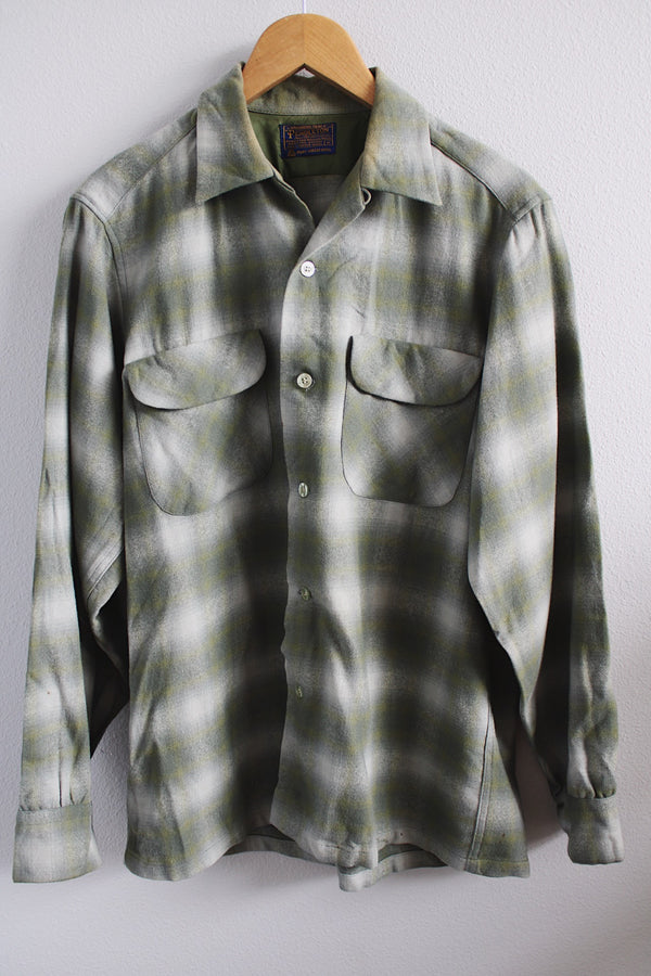 Men's vintage 1960's Pendleton size medium long sleeve button up wool shirt in all over green and white plaid print. Two chest pockets.