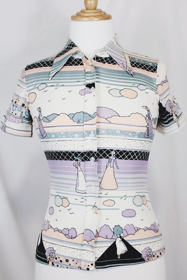Women's vinttage 1970's Fritz label short sleeve button up blouse with dagger collar and all white, blue, and purple novelty print in a lightweight polyester material. 