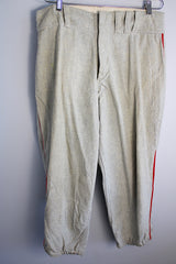 Men's vintage 1940's Rawlings, St. Louis label capri length baseball pants in grey wool material with red stripe piping along each side of leg.