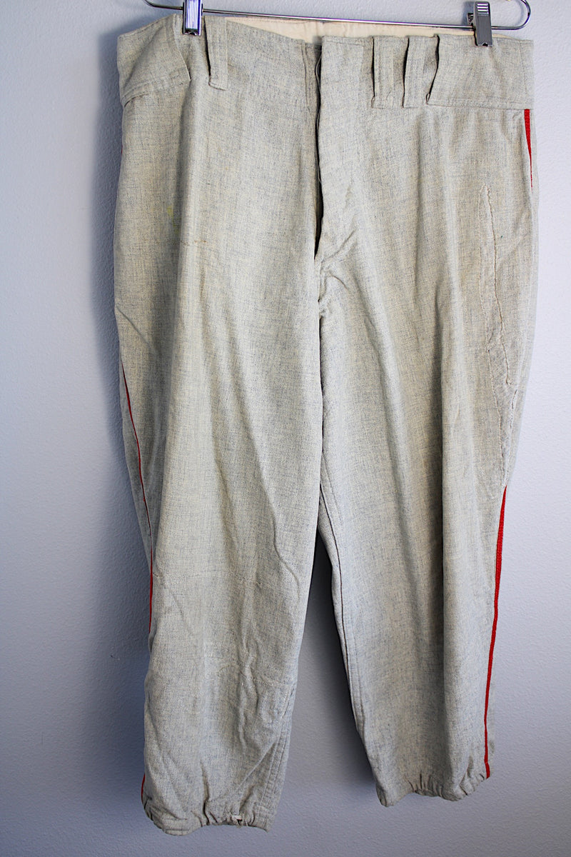 Men's vintage 1940's Rawlings, St. Louis label capri length baseball pants in grey wool material with red stripe piping along each side of leg.