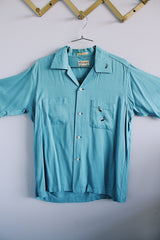 Men's vintage 1950's Skipper, Wilson Brothers, Made in USA, Custom Detailed label short sleeve blue button up shirt in cotton material with small embroidered skunks. 