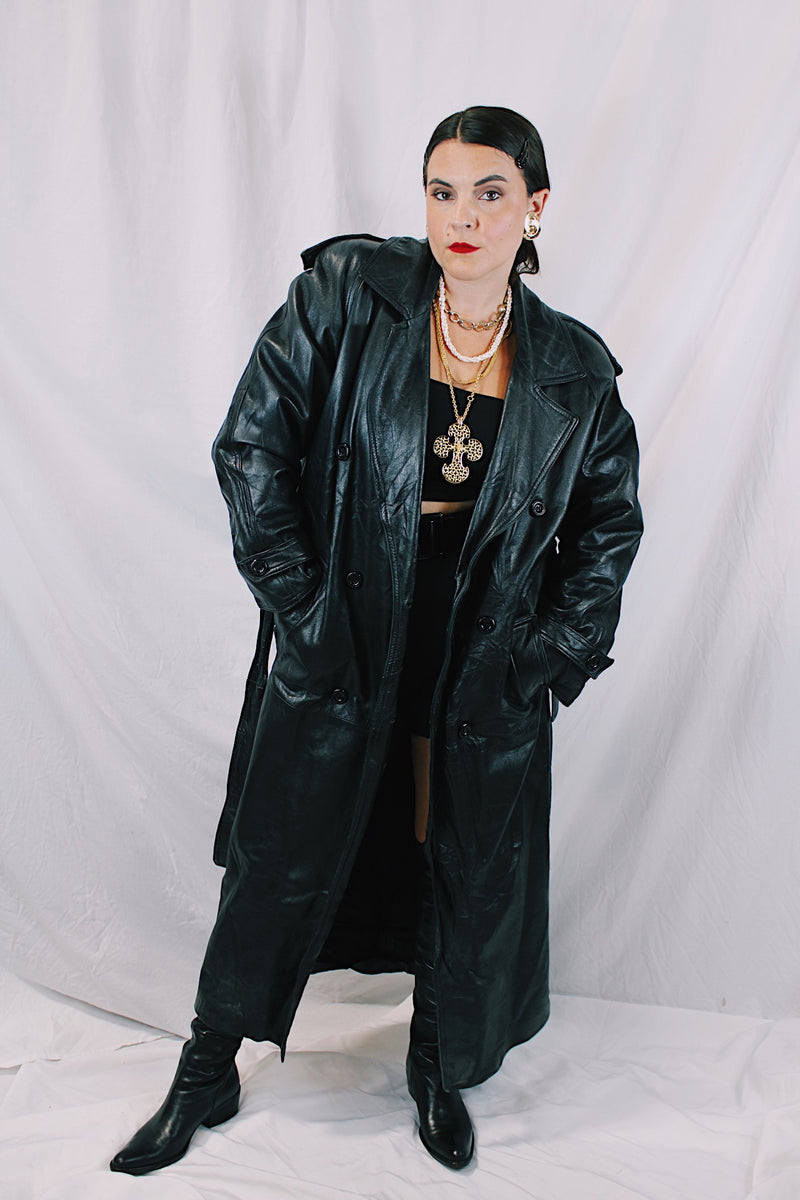 Men's or women's vintage 1980's Vakko Sport, Made in USA label long sleeve long length black leather trench coat. Double breasted closure, shoulder pads, and matching tie belt.
