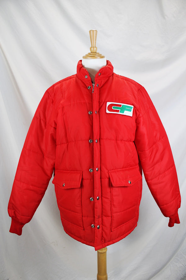 Women's or men's vintage 1980's Tonkin Wearables, Woodinville, WA, Made in USA label long sleeve bright red nylon puffer jacker with patch on left chest and a zipper and popper buttons closure. 