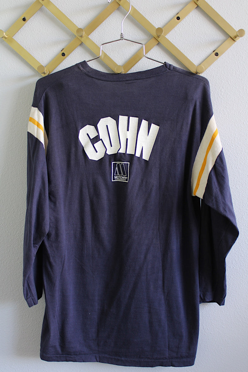 Women's or men's vintage 1970's Sportswear label long sleeve navy blue Stephen Cohn tee with white and yellows stripes on arms. White graphic with text on front and back.