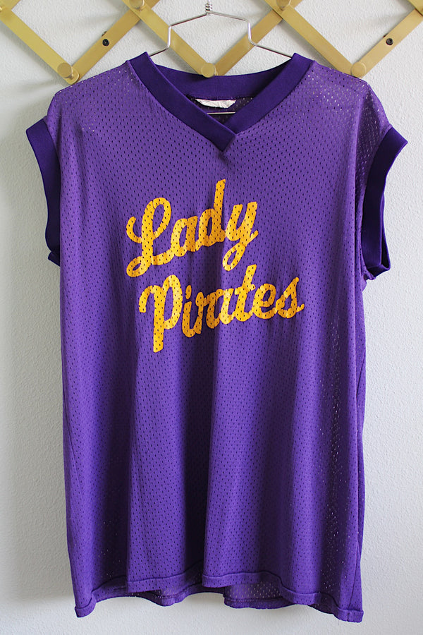 Women's vintage 1990's Doherty & Dunne Sporting Goods label sleeveless mesh nylon material sports jersey tee with ribbed knit trim. Purple with yellow letters that say lady pirates.