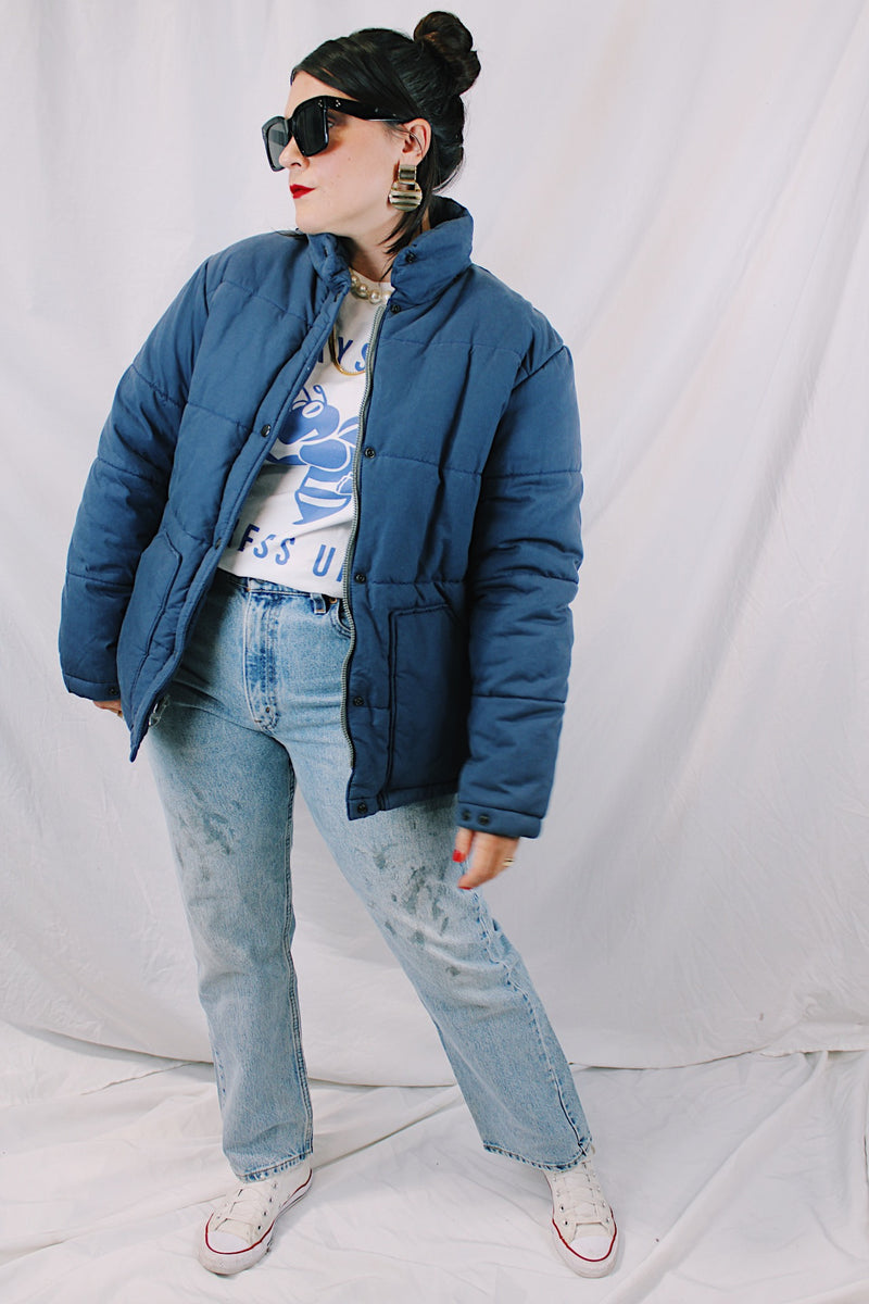 Men's or women's vintage 1980's long sleeve navy blue puffer jacket with zipper, popper buttons, and pockets. Cotton and polyester materials.