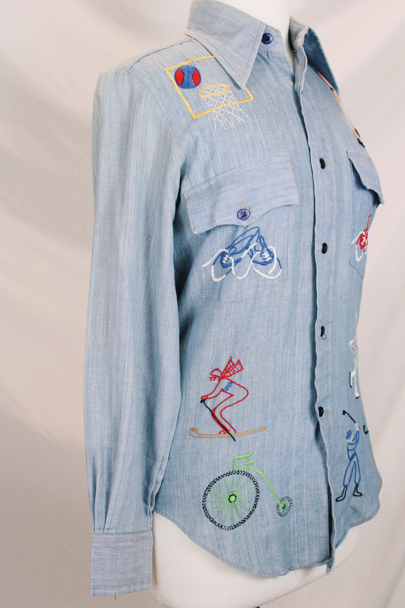 Men's or women's vintage 1970's BJ-R, Long Tail - Form Fit, Made in Hong Kong label long sleeve light blue denim chambray button up shirt with colored embroidery all over.