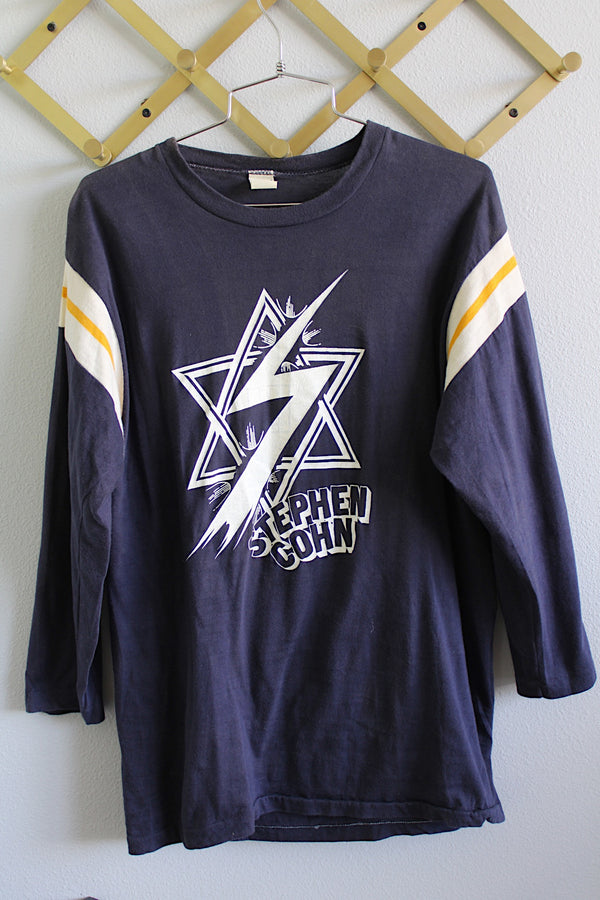Women's or men's vintage 1970's Sportswear label long sleeve navy blue Stephen Cohn tee with white and yellows stripes on arms. White graphic with text on front and back.
