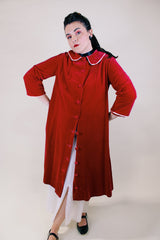 Women's vintage 1960's long length long sleeved red velvet robe duster with a peter pan collar and pink stain trim. Buttons up the front.