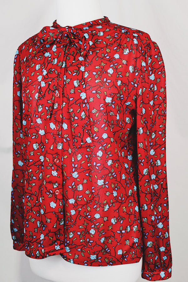 Women's vintage 1970's Donnkenny label long sleeve button up blouse with an attached tie neck. Red with all over blue ditsy floral print. 